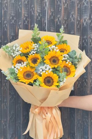 Bó hoa hướng dương rực rỡ tượng trưng cho niềm tin, hy vọng và sự lạc quan. Những bông hoa vàng tươi tắn tỏa năng lượng tích cực, được gói tinh tế, mang đến vẻ đẹp vui tươi, ấm áp và đầy sức sống, thích hợp để tặng bạn bè, đồng nghiệp hoặc chúc mừng thành công.