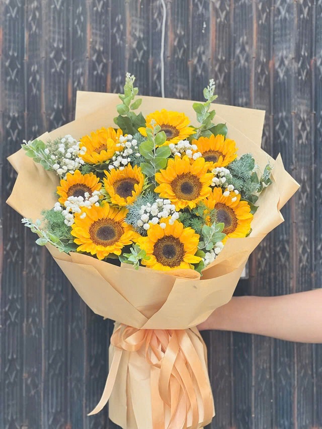 Bó hoa hướng dương rực rỡ tượng trưng cho niềm tin, hy vọng và sự lạc quan. Những bông hoa vàng tươi tắn tỏa năng lượng tích cực, được gói tinh tế, mang đến vẻ đẹp vui tươi, ấm áp và đầy sức sống, thích hợp để tặng bạn bè, đồng nghiệp hoặc chúc mừng thành công.