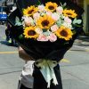 Bó hoa hướng dương mix hồng kem giấy đen mang vẻ đẹp hiện đại và cuốn hút, với sắc vàng rực của hướng dương hòa cùng tone hồng kem nhẹ nhàng trên nền giấy đen sang trọng. Tổng thể tạo nên sự tươi sáng, tinh tế và đầy năng lượng tích cực, thích hợp để tặng trong dịp chúc mừng hoặc tri ân đặc biệt.