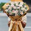 Bó hoa hồng kem gói giấy báo vintage, thanh lịch và tinh tế.