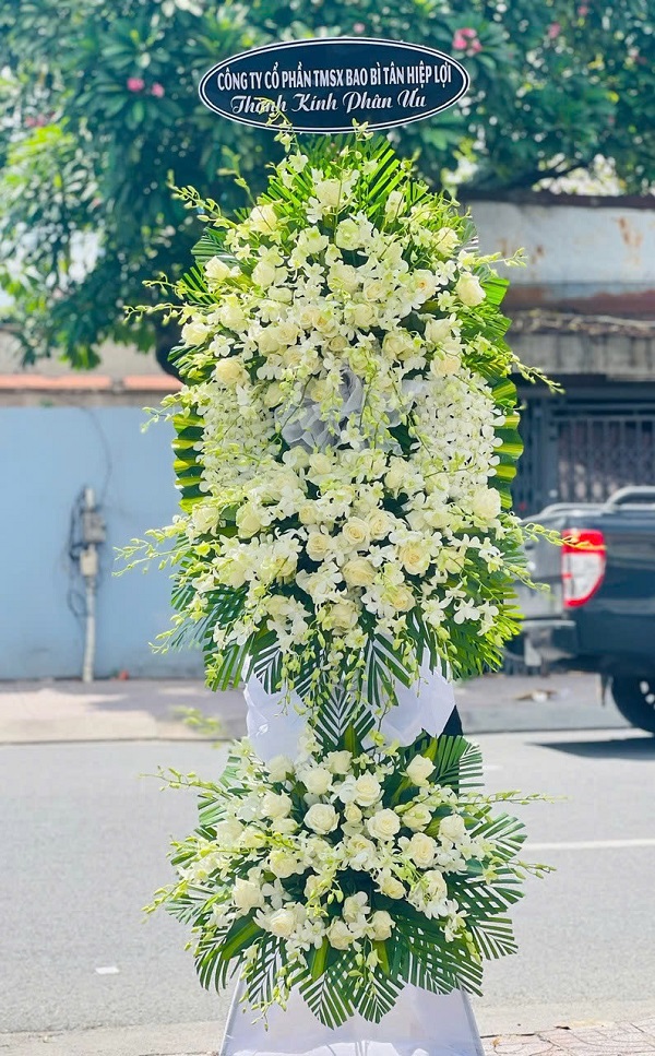 Kệ hoa viếng lan trắng phối cúc 2 tầng đẹp, trang nhã và thanh khiết, thể hiện sự kính trọng và niềm tiếc thương sâu sắc dành cho người đã khuất.