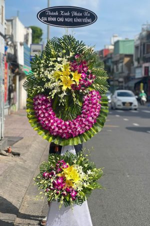 Kệ hoa viếng 2 tầng kết hợp lan tím, lan trắng và ly vàng, thiết kế trang nhã, sang trọng, thể hiện lòng thành kính.