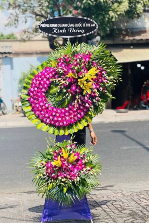Kệ hoa viếng 2 tầng nổi bật với lan tím kết hợp ly vàng, tạo vẻ sang trọng và trang nghiêm, thể hiện tấm lòng thành kính.