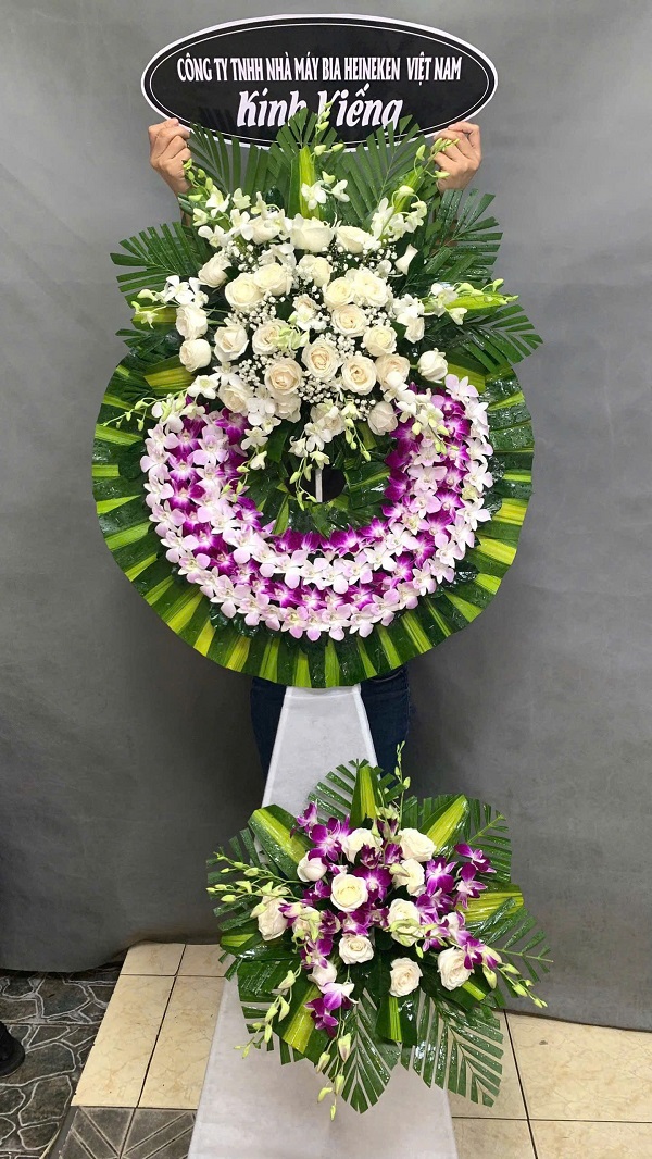 Vòng hoa chia buồn với tông màu trắng và tím, biểu tượng của sự kính trọng và tiếc thương. Dịch vụ điện hoa chia buồn tại Châu Đức, Bà Rịa – Vũng Tàu giúp bạn gửi lời tiễn biệt đến người đã khuất.