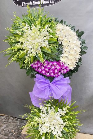Kệ hoa viếng 2 tầng trang nhã, kết hợp lan trắng, lan tím và cúc trắng, mang vẻ thanh khiết và trang trọng, thể hiện lòng thành kính.